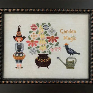 Framed cross-stitched artwork with a scarecrow, flowers, and a bird on a white background.